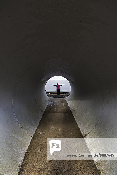 A person with outstretched arms standing at the end of a tunnel; Kielder  Northumberland  England