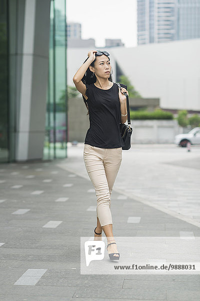 Young woman walking in business district; Xiamen  China