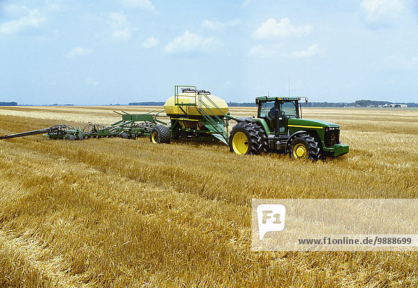 Agriculture - A tractor pulls an air seeder planting no-till double crop soybeans in wheat stubble / Arkansas  USA.