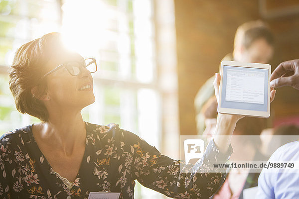 Woman using digital tablet in sunny meeting