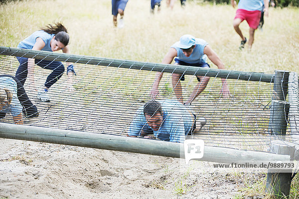 People crawling under net on boot camp obstacle course