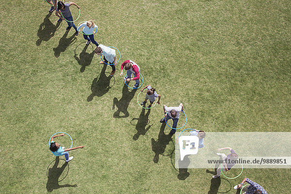 People spinning in plastic hoops in sunny field