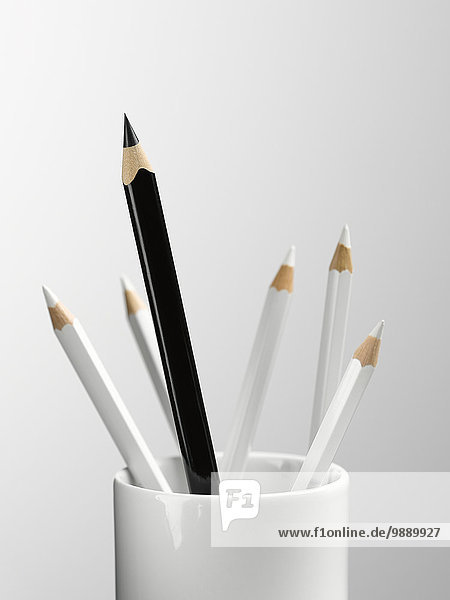 Großer schwarzer Bleistift im Becher mit kleinerem weißen Bleistift-Stilleben