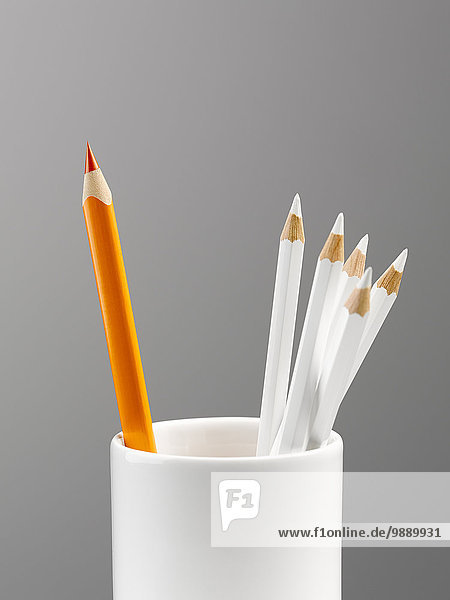 Orangenstift im Becher mit weißem Bleistift-Stilleben getrennt