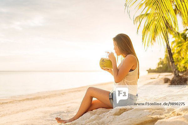 Young woman drinking fresh coconut milk on Anda beach  Bohol Province  Philippines