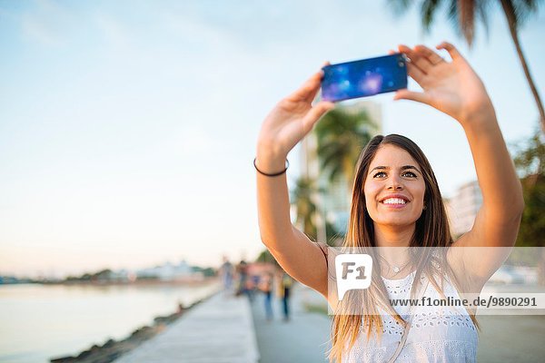 Junge Frau mit Smartphone Selfie am Wasser  Manila  Philippinen