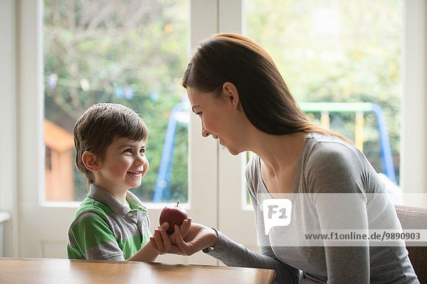 Boy smiling at mother as he hands her apple