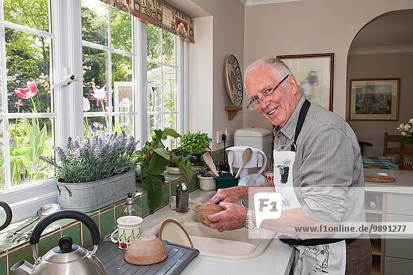Senior man in kitchen  washing dishes