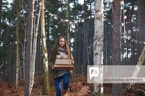 Geschenke  die von einer jungen Frau durch den Wald getragen werden.