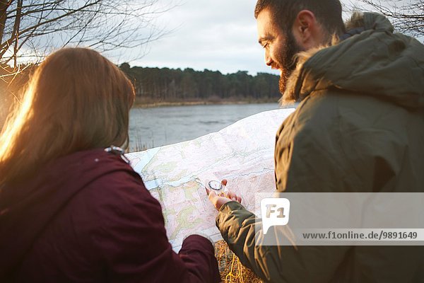 Young couple at lakeside reading map