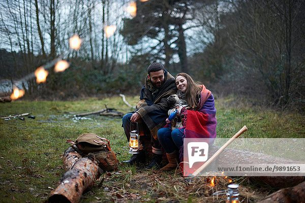 Junges Camping-Pärchen mit Hund in Walddecke gewickelt