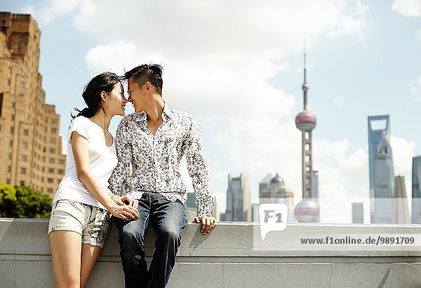 Romantic tourist couple sitting on wall  The Bund  Shanghai  China