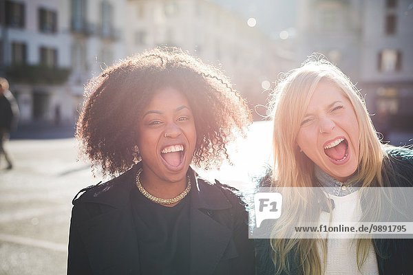Portrait of two laughing female friends in town square
