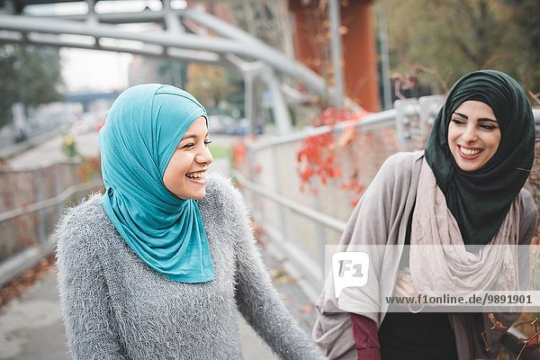 Two young female friends laughing on park path