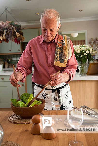 Senior Mann bereitet Salat in der Küche zu
