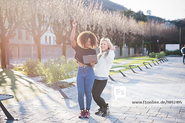 Two young female friends in park laughing at digital tablet  Como  Italy