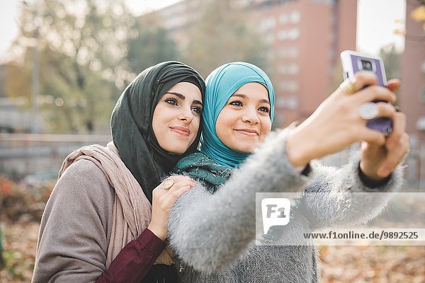Zwei Freundinnen im Park posieren für Smartphone Selfie