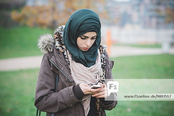Young woman in park texting on smartphone