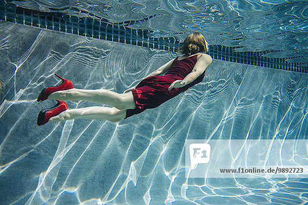 Reife Frau in rotem Kleid und High Heels  schwimmend  Unterwasseransicht
