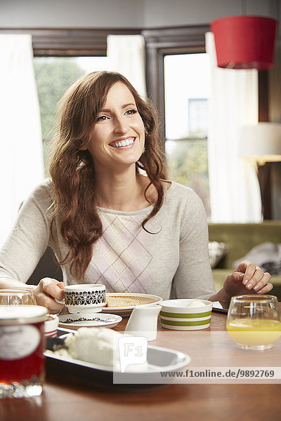Young woman drinking breakfast coffee in kitchen