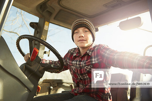 Porträt eines jungen Landwirts mit Traktor auf einem Milchviehbetrieb