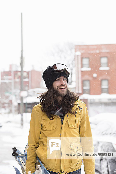 Lächelnder Snowboarder in schneebedeckter Straße