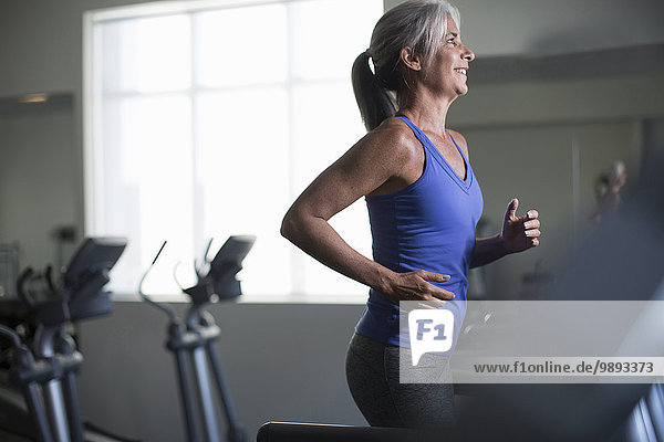Mature woman running on gym treadmill