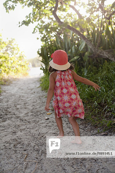 Rückansicht des barfüßigen Mädchens im Sonnenhut beim Spaziergang am Waldstrand  Anna Maria Island  Florida  USA