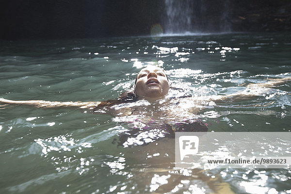 Schwimmende Frau  Wasserfall im Hintergrund