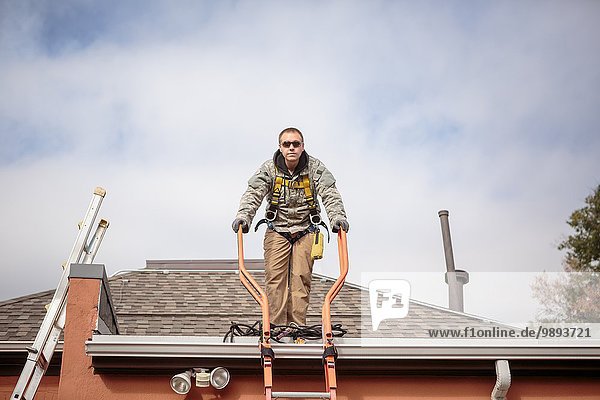 Solar panel installation worker on roof of house