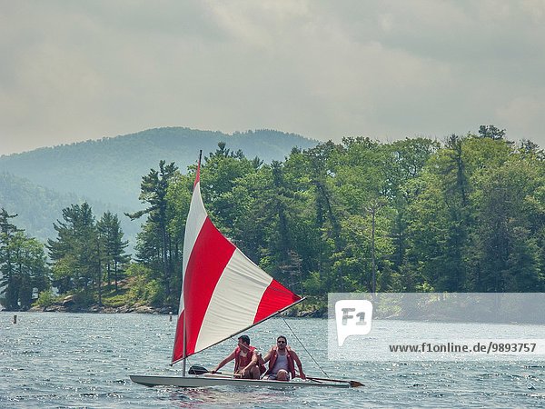 Two men in a small sailboat on Lake George  New York  USA