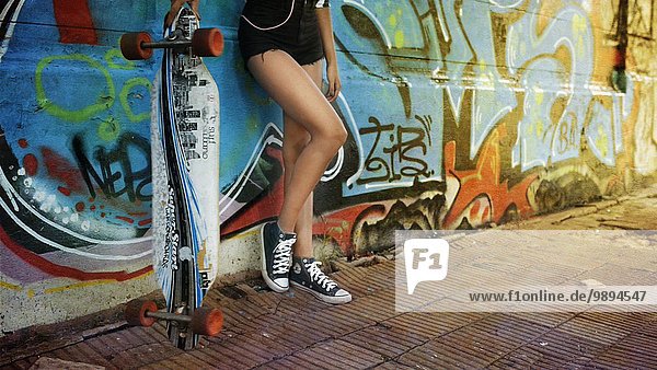 angelehnt junge Frau junge Frauen Portrait Wand halten Skateboard herumwirbeln lang langes langer lange Unterer Ausschnitt Graffiti