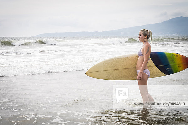 Mexiko  Riviera Nayarit  junge Frau mit Surfbrett am Meer