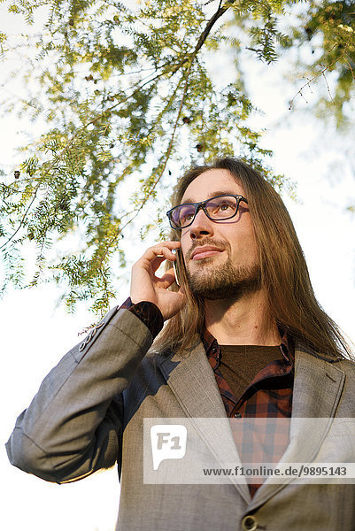 Portrait des langhaarigen Hipster-Telefonierens mit Smartphone