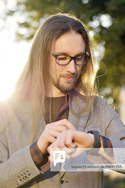 Langhaariger Hipster mit smartwatch