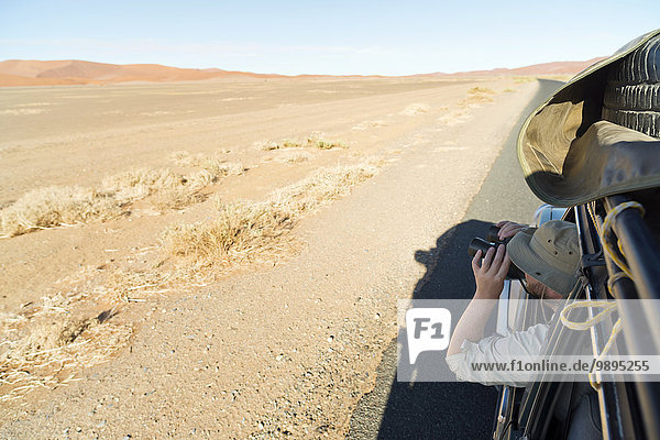 Namibia  Namib Desert  Namib Naukluft Park  Sossusvlei  man in a car looking through binoculars