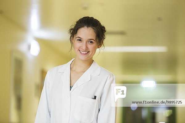 Porträt eines lächelnden jungen Arztes auf dem Krankenhausboden