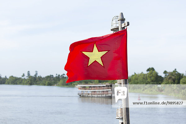 Vietnam  Flagge und Holzschiff auf dem Mekong River