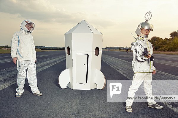 Zwei Jungen verkleidet als Raumfahrer an der Papprakete stehend