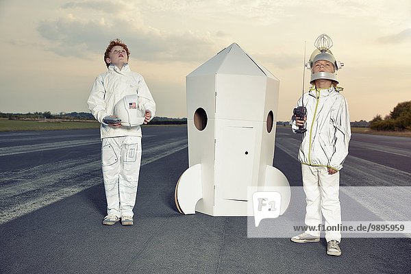 Zwei Jungen verkleidet als Raumfahrer an der Papprakete stehend