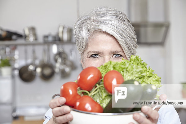 Reife Frau hält Topf mit Gemüse