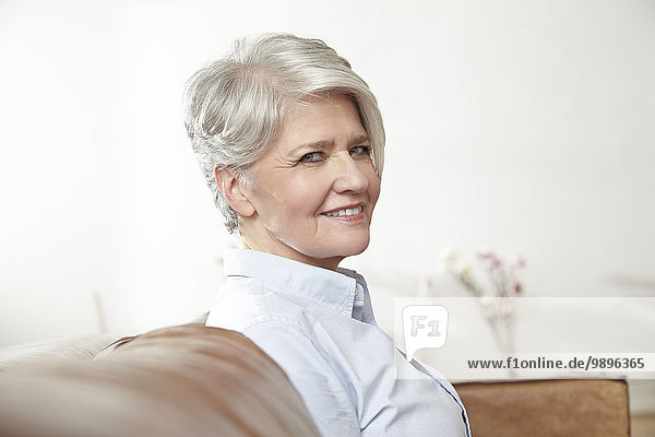 Portrait of smiling mature woman sitting on couch