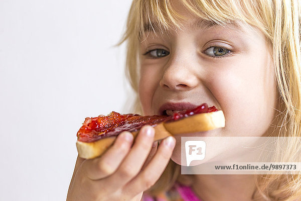 Porträt eines blonden Mädchens beim Brotessen mit Marmelade