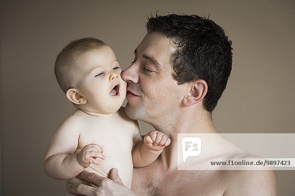 Portrait of man kissing baby girl