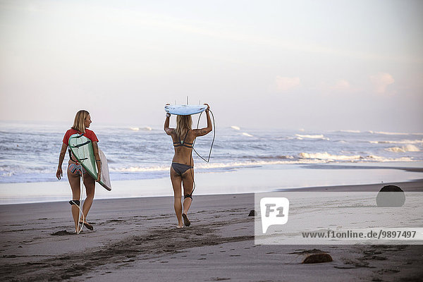 Indonesien  Bali  zwei Frauen mit Surfbrettern am Strand