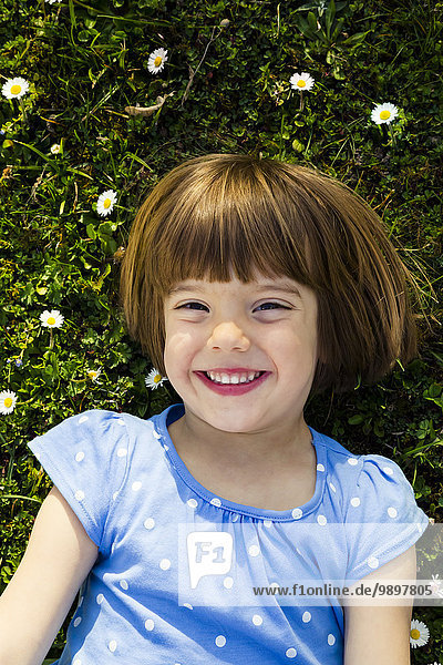 Portrait of happy little girl lying on a meadow