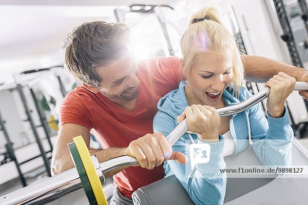 Training für junge Paare mit EZ Curl Bar im Fitnessstudio
