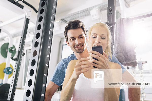 Young couple with smartphone after training at gym