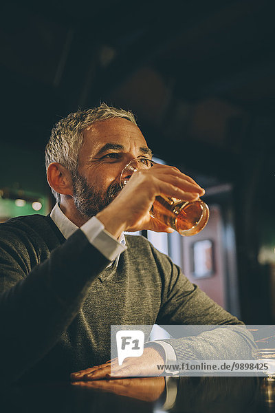 Mann am Tresen einer Kneipe beim Biertrinken