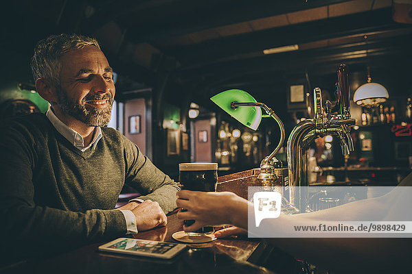 Smiling man sitting at counter of a pub